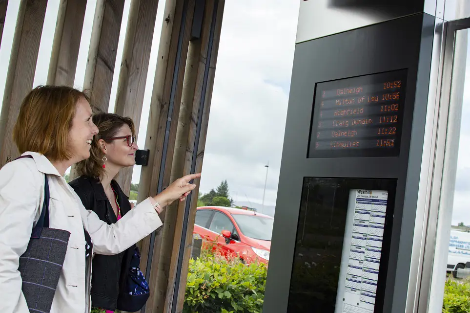Two women looking at RTI at bus  stop on Inverness Campus