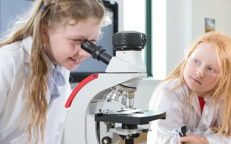 Girls with microscope in STEM Hub at Inverness Campus